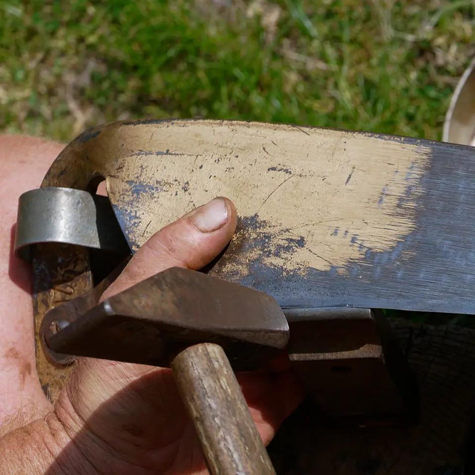 Peening - repairing a damaged scythe blade with a peening stool and hammer